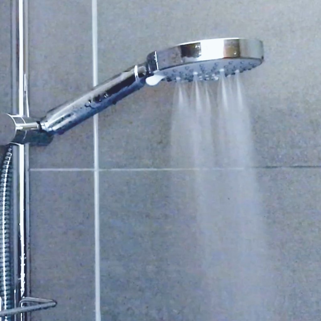 Duschkopf an einer Duschstange mit laufendem Wasser