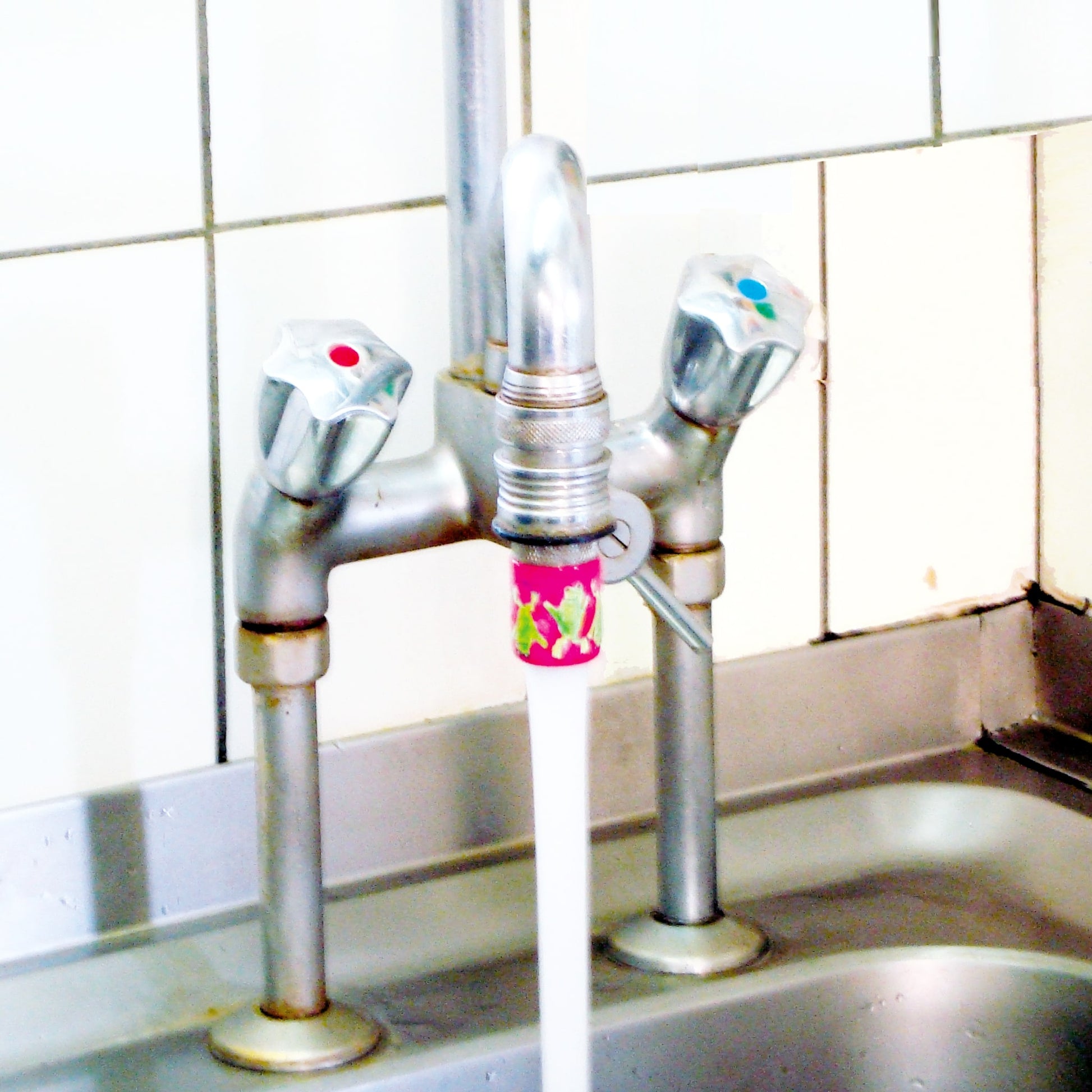 pinkfarbener Gastro-Adapter an einem Grossküchen-Wasserhahn, angeschraubt dank Gastro-Adapter