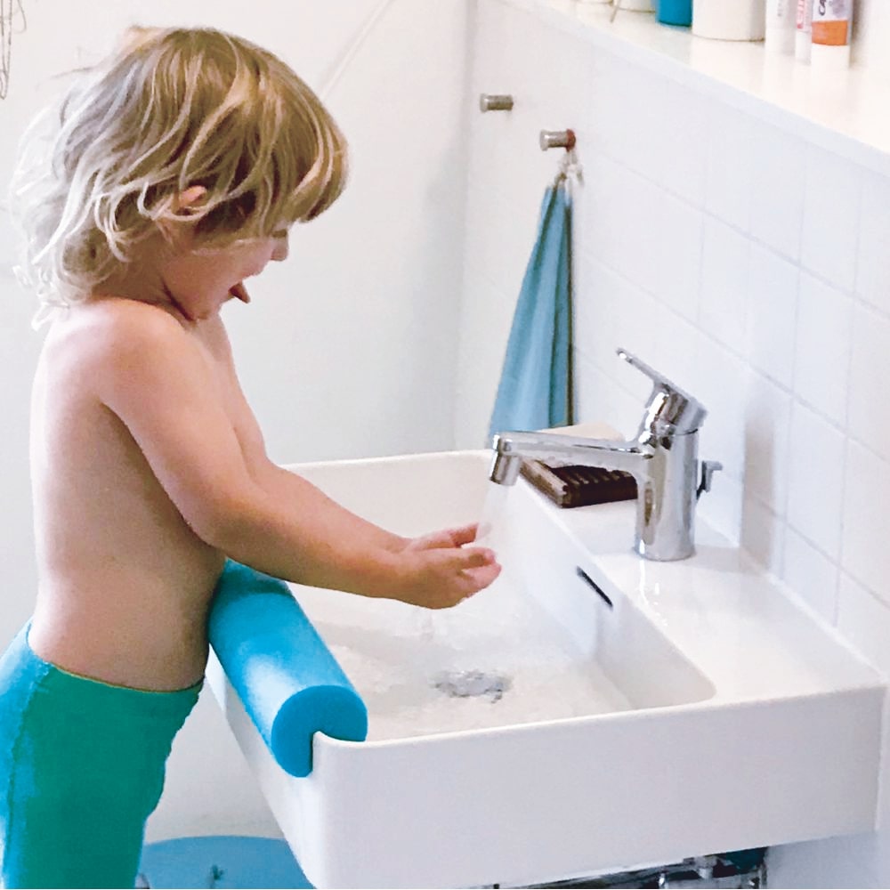 Un petit garçon se lave les mains au robinet équipé d'AquaClic.